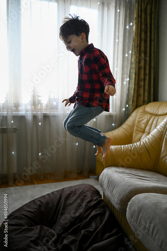 Vászonkép little boy at home having fun and jumping on the couch