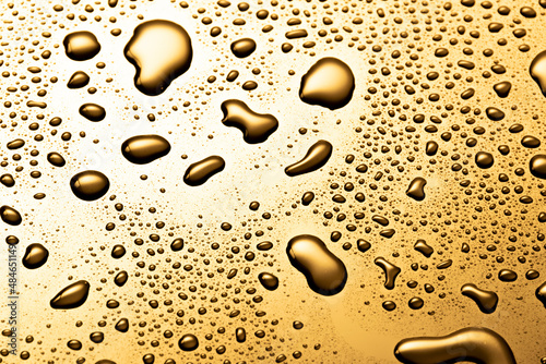 Golden metal water drops on  reflective surface