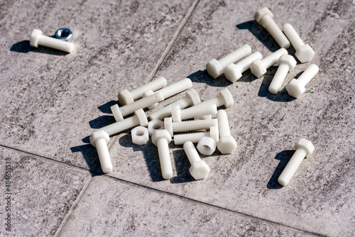 Plastic screws and nuts on ceramic tiles close up