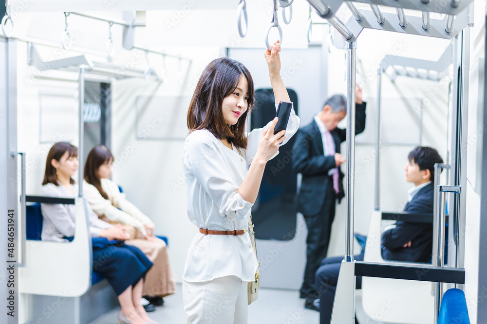 電車でスマホを使う若い女性