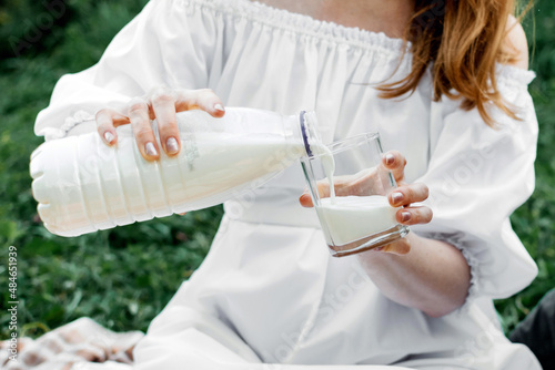A girl in a white dress is pouring milk in the park