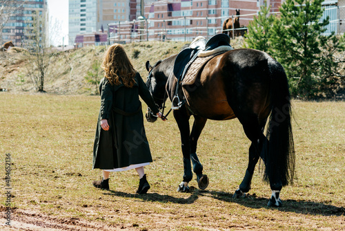 Girl walking with a horse on a ranch in summer