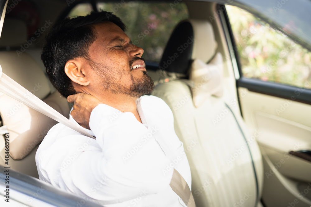 Tired young indian cab driver suffering from neck joint pain due to