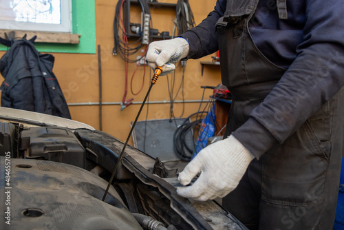 Car mechanic checking oil level in a mechanical workshop.