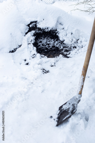 Black coal covered with snow and a shovel. Heating of a residential building in the countryside
