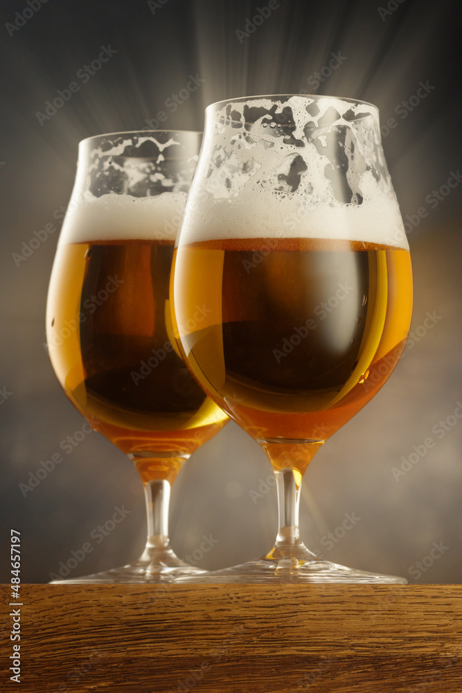 Two Glass of light beer on wooden table and dark background. Shallow depth of field	