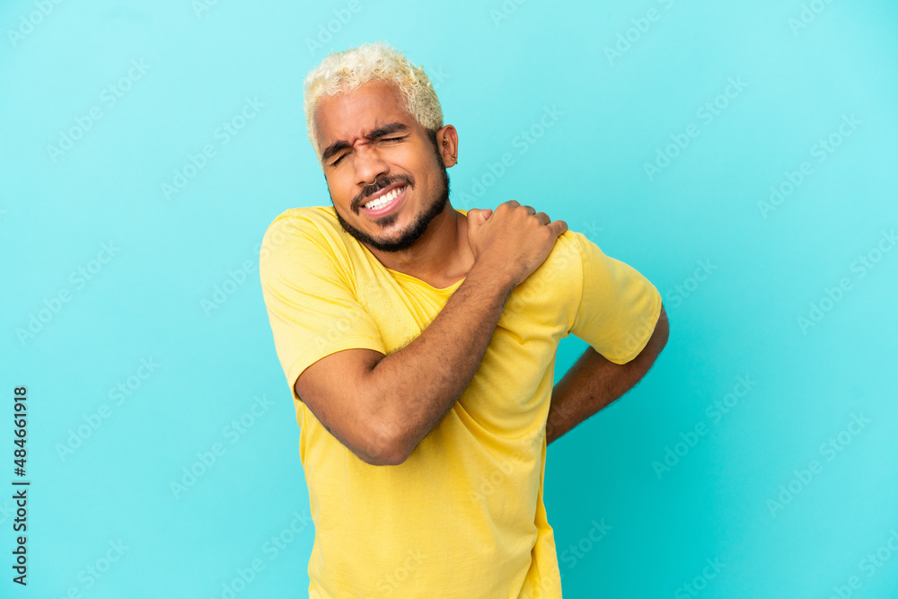 Young Colombian handsome man isolated on blue background suffering from pain in shoulder for having made an effort