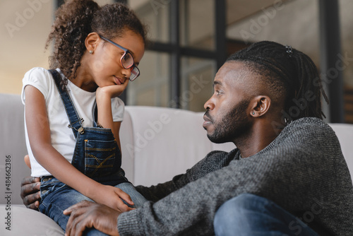 Loving african-american father dad listening to daughter`s problems with attention, supporting and calming her at home. Solving family problems. Fatherhood. photo