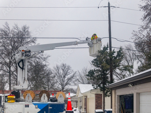 Technician lineman in bucket truck repairing overhead lines after snow storm