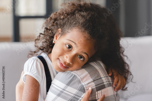 Little small cute african daughter girl preteen child kid hugging embracing mother mom nanny childminder with love and care. Motherhood and adoption. Mother`s protection.