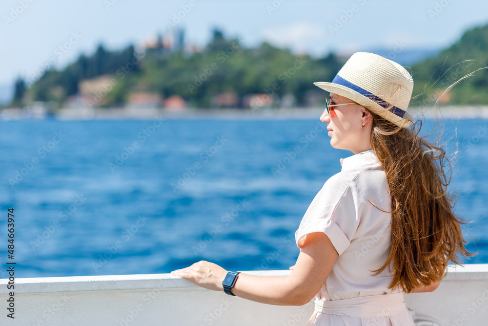Young lady in dress travelling by ship on her vacation cruise in europe. Smiling woman enjoying sunny day at the sea