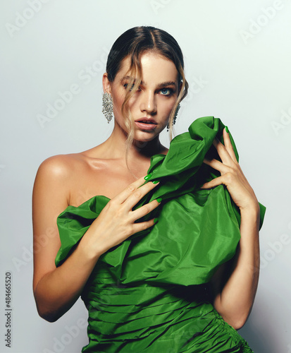 Portrait of a beautiful young woman with bright makeup and in a bright green dress. Advertising of fashionable clothes, decorative cosmetics advertising concept. Fashionable dress.