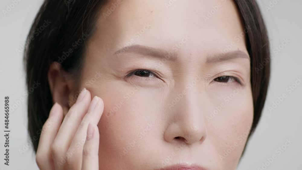 Closeup Of Middle Aged Japanese Woman Touching Wrinkles, Gray Background Closeup Of Middle Aged Japanese Woman Touching Wrinkles, Gray Background