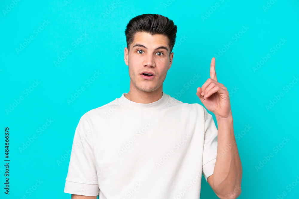 Young handsome caucasian man isolated on blue bakcground thinking an idea pointing the finger up Young handsome caucasian man isolated on blue bakcground thinking an idea pointing the finger up