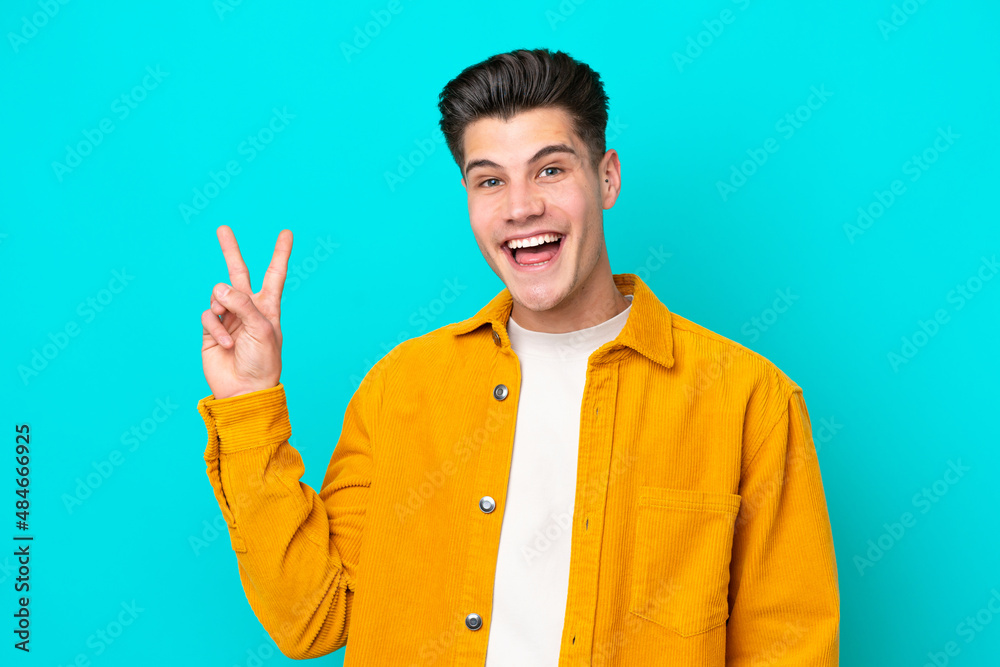 Young handsome caucasian man isolated on blue bakcground smiling and showing victory sign Young handsome caucasian man isolated on blue bakcground smiling and showing victory sign
