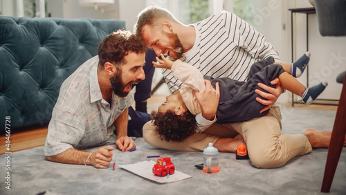 Фотография Loving LGBTQ Family Playing with Toys with Adorable Baby Boy at Home on Living Room Floor
