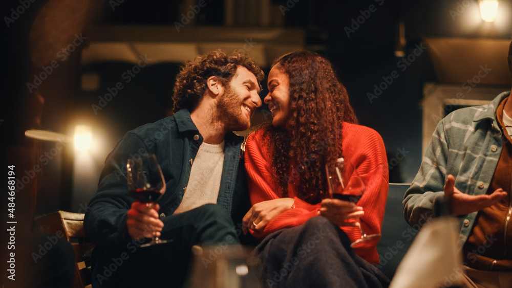 Loving Mixed Race Couple Sitting Together at a Garden Party Celebration with Friends on a Warm Summer Evening. Beautiful Man and Woman Kiss, Talk, Relax on Weekend, Have Fun and Drink Wine.