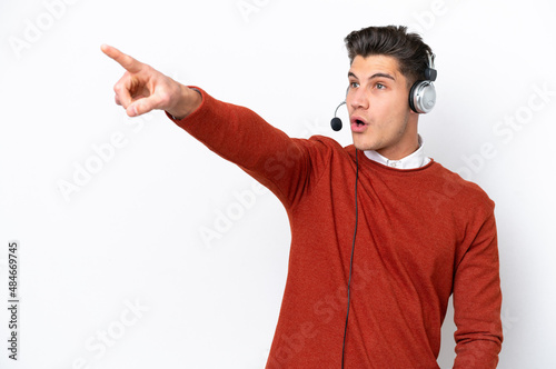 Telemarketer caucasian man working with a headset isolated on white background pointing away