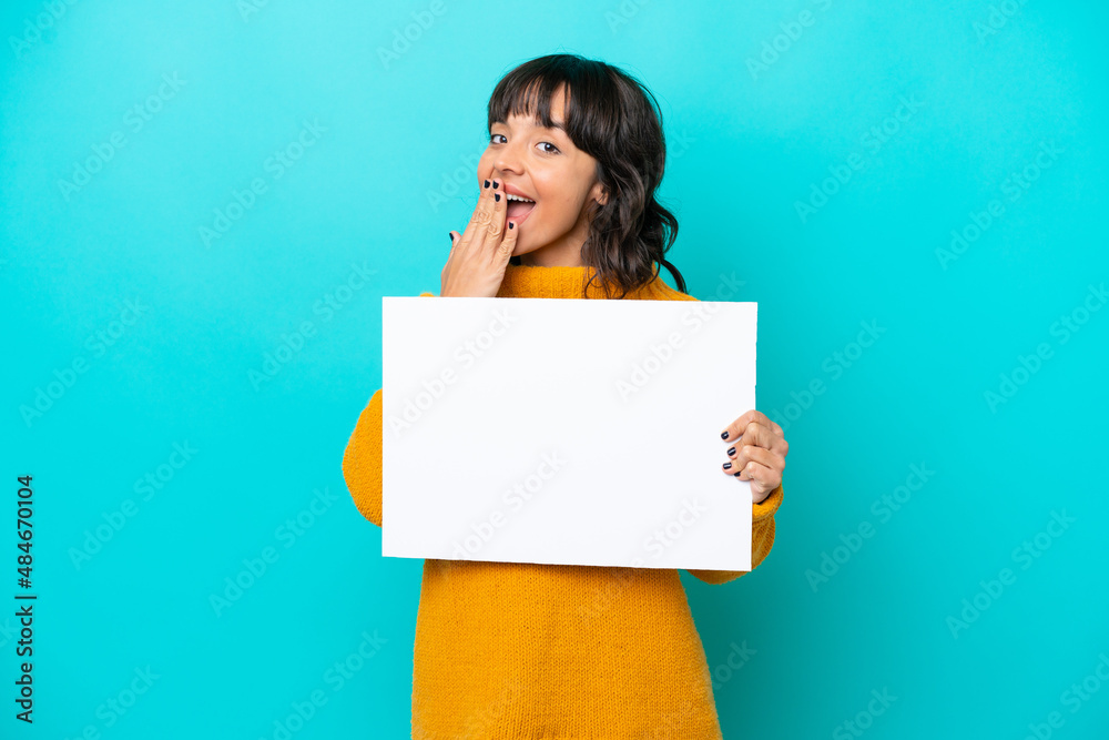 Young latin woman isolated on blue background holding an empty placard with surprised expression Young latin woman isolated on blue background holding an empty placard with surprised expression
