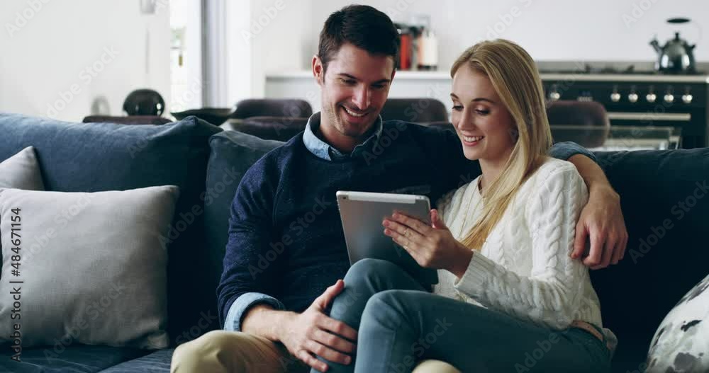 Stay in, stay connected. A young happy smiling couple using a digital tablet on the sofa at home. Smiling man and woman relaxing in the lounge together online Stay in, stay connected. A young happy smiling couple using a digital tablet on the sofa at home. Smiling man and woman relaxing in the lounge together online