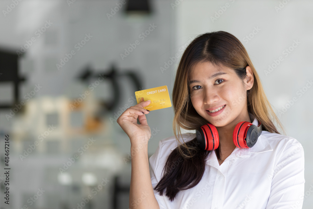 Pretty Asian woman smiling and happy holding a credit card. Pretty Asian woman smiling and happy holding a credit card.