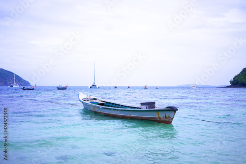 Island in the middle of the sea and boats moored in the sea © TEEREXZ