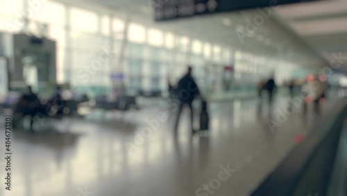 Defocused people walking at the airport with their luggage and backpacks photo