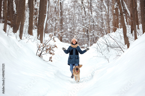 The dog walks in the winter in nature with its owner. They train and play. 