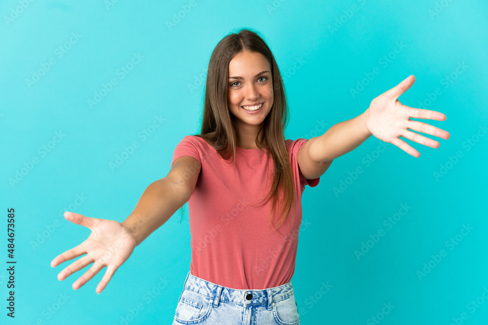 Young woman over isolated blue background presenting and inviting to come with hand Young woman over isolated blue background presenting and inviting to come with hand