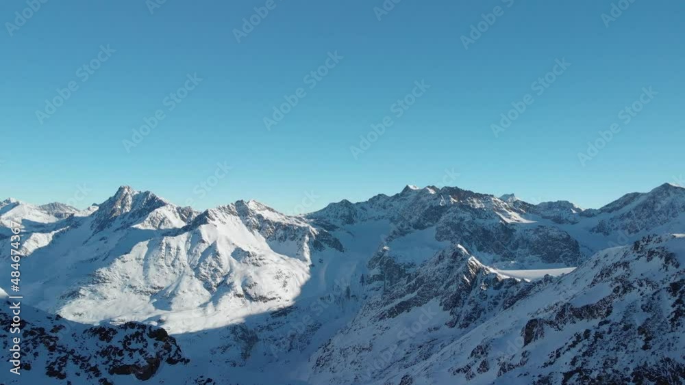 Aerial view overlooking rocky mountain ranges, snowy winter landscape - reverse, drone shot Aerial view overlooking rocky mountain ranges, snowy winter landscape - reverse, drone shot