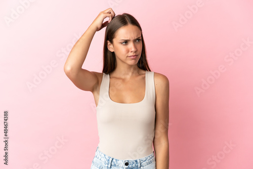 Young woman over isolated pink background having doubts while scratching head