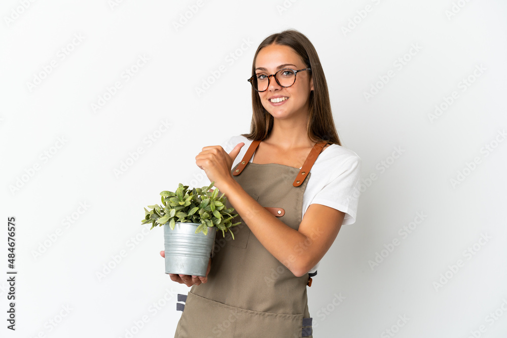 Gardener girl holding a plant over isolated white background proud and self-satisfied Gardener girl holding a plant over isolated white background proud and self-satisfied
