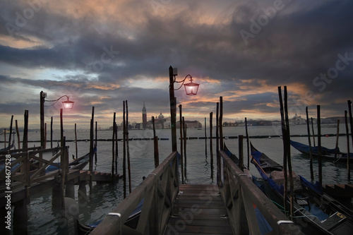 Tela Espectacular vista desde el centro de un embarcadero de Venecia con góndolas amarradas a los costados en un cielo de  atardecer rojizo y oscuro
