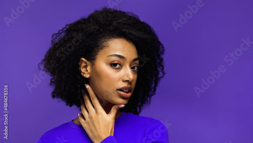 pretty african american woman with curly hair isolated on purple.