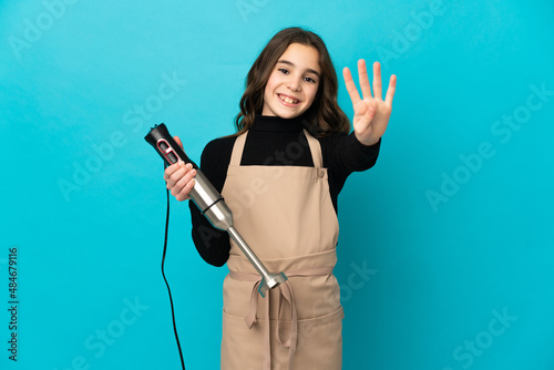 Little girl using hand blender isolated on blue background happy and counting four with fingers