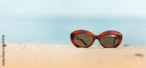 Vintage Brille an einem Sandstrand mit blauem Meer im Hintergrund