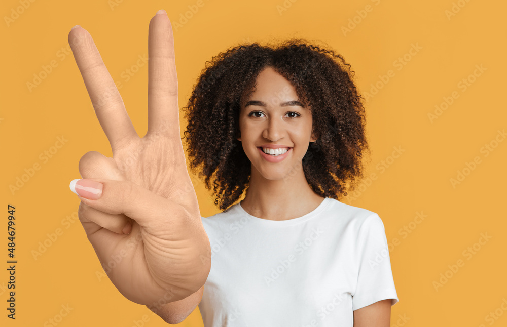 Cheerful mixed race young lady showing peace gesture Cheerful mixed race young lady showing peace gesture