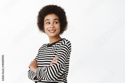 Portrait of beautiful young modern girl, black woman with afro hair, smiling and looking confident at camera, healthy people and lifestyle concept, white background