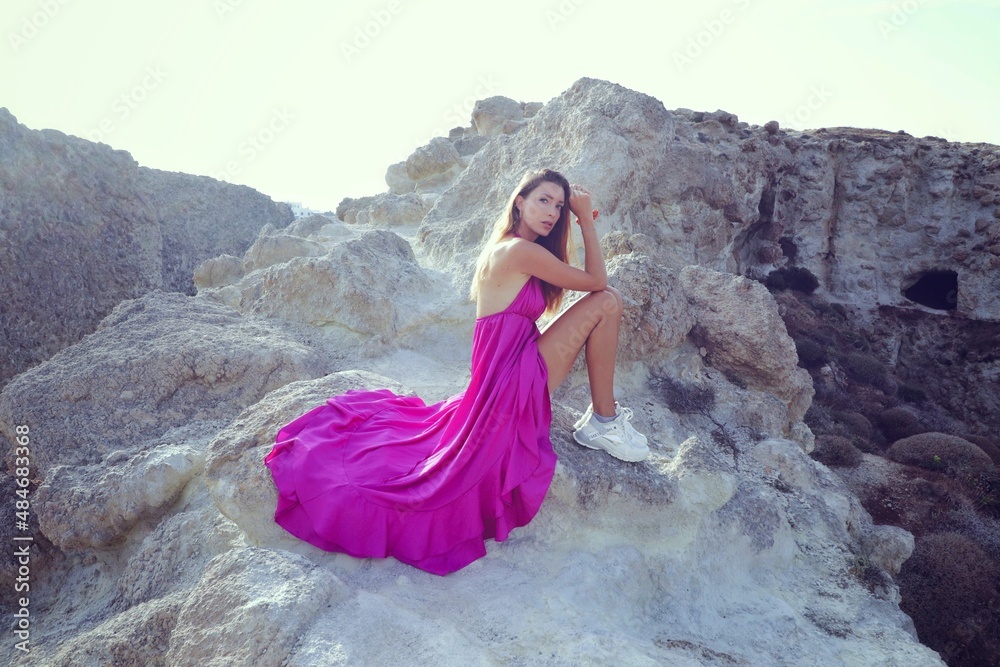 woman in a pink dress on a beach in milos greece woman in a pink dress on a beach in milos greece