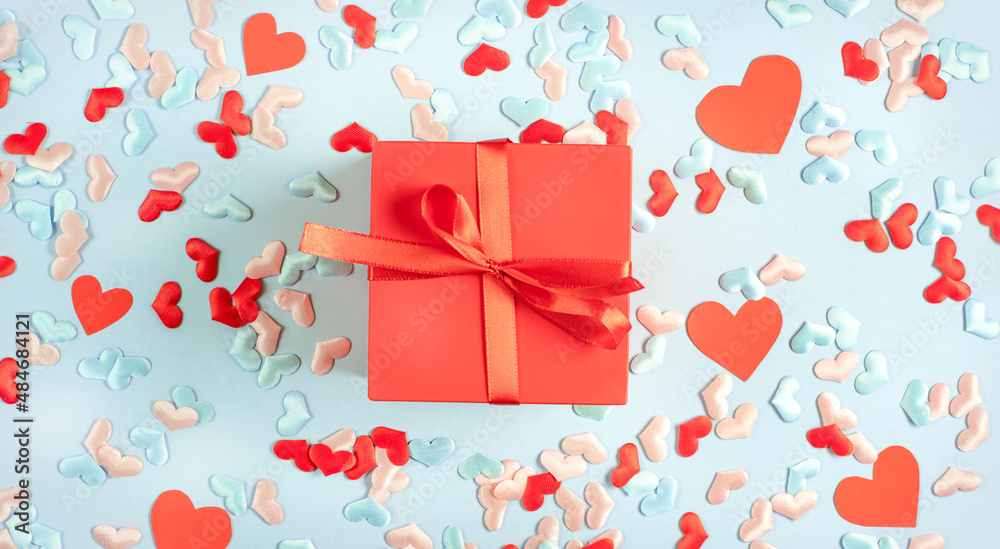Red present gift box on Blue background with multicolored hearts.