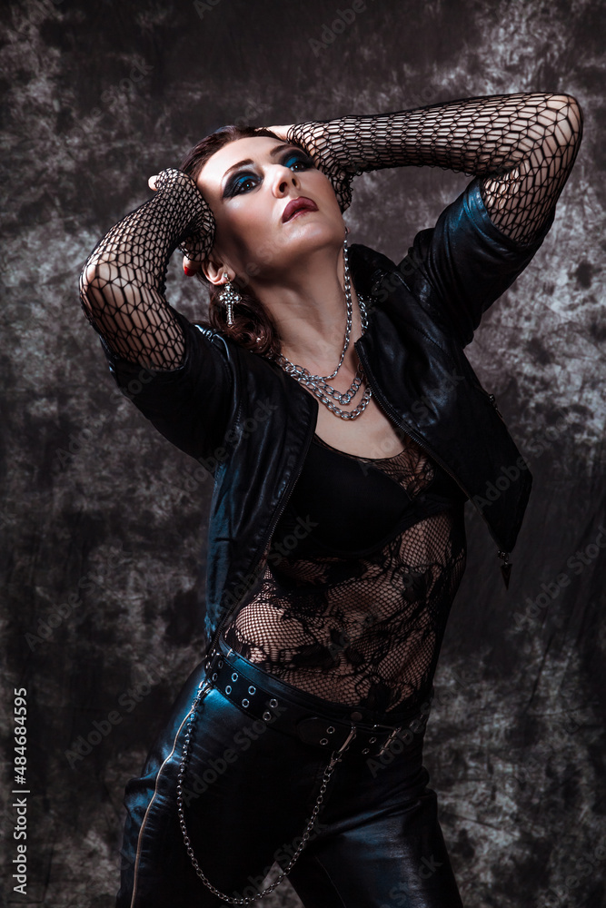 Stylish sexy brunette girl in a dramatic gothic rock-style image leather  jacket with chains posing on a dark background Stock Photo | Adobe Stock