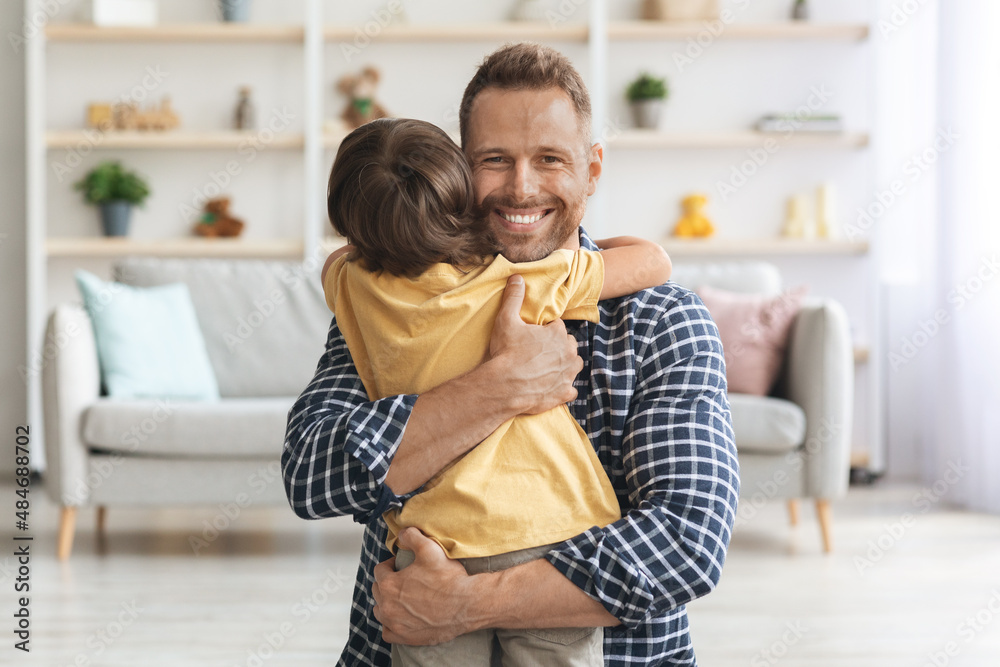 Sincere kid love. Cute little son embracing his lovely daddy, happy man smiling to camera, enjoying boy's hugs Sincere kid love. Cute little son embracing his lovely daddy, happy man smiling to camera, enjoying boy's hugs