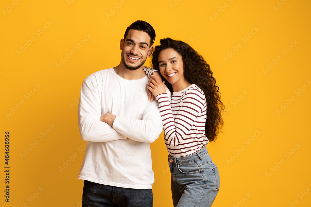 Happy Millennials. Portrait Of Smiling Young Middle Eastern Couple Posing Over Yellow Background Happy Millennials. Portrait Of Smiling Young Middle Eastern Couple Posing Over Yellow Background