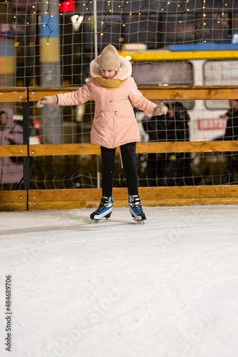 girl tries to skate on the ice rink
