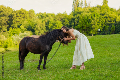 Billede på lærred woman petting a pony standing on the lawn