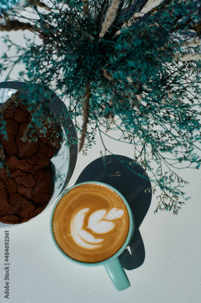 Morning cappuccino in coffee shop on summer terrace with flowers and chocolate cookies.