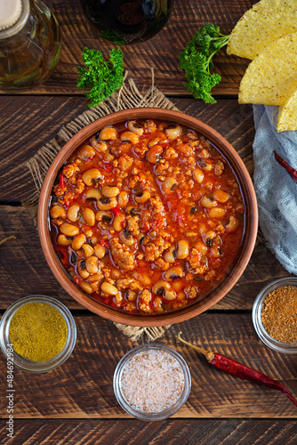 Chili con carne in a bowl on wooden background. Mexican cuisine. Top view