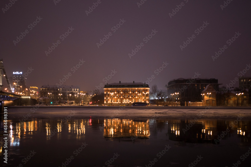 Night embankment with reflection of buildings and lights with gold colours