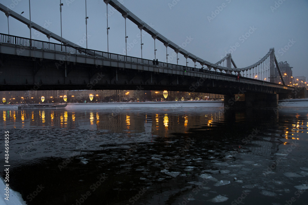 The beautiful view on the bridge in the night and golden reflection in the river with ice The beautiful view on the bridge in the night and golden reflection in the river with ice