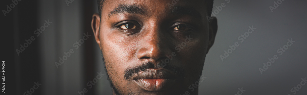 Obraz premium Depressed African man thinking about disappointed love and looking down in dark room.Concept of Broken Heart and Valentine's Day